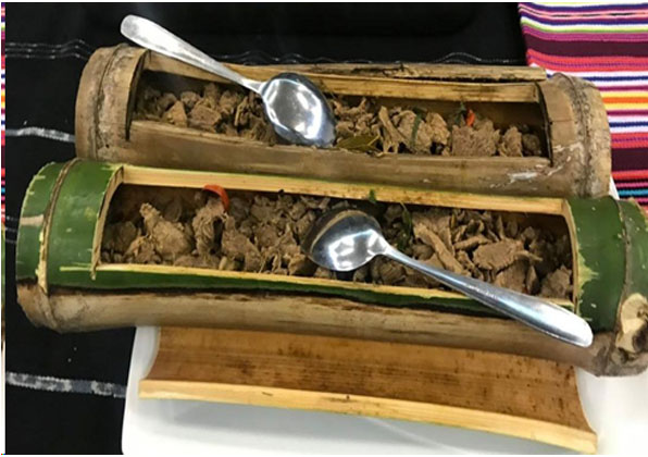 Tukir, o prato tradicional de Timor-Leste feito com carne marinada cozida dentro de um tubo de bambu, destacando o método culinário ancestral pré-colonial das regiões montanhosas.