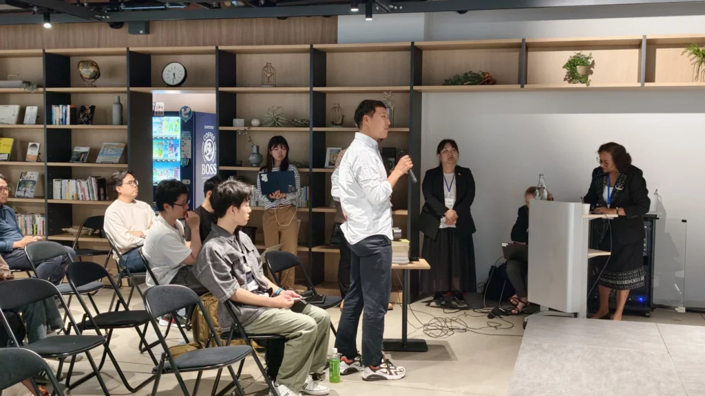 Student asking a question during the presentation session at Hiroshima University.